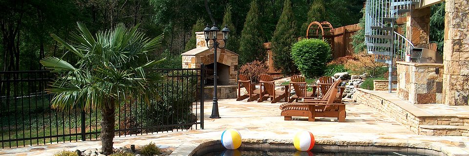 A backyard patio and pool behind a stone home